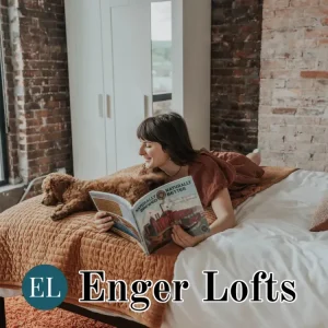Woman reading a magazine on a bed with a dog in a cozy loft setting.